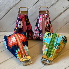 three colorful purses with zippers on them sitting on a table next to each other