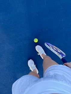 a person standing on a tennis court holding a racquet next to a ball