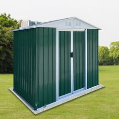 a green and white shed sitting in the middle of a grass field next to trees