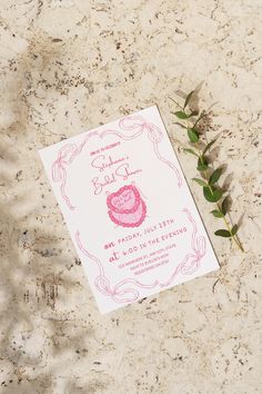 a pink and white baby's first birthday party card on a marble surface next to a green plant