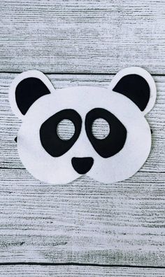 a panda mask with black and white eyes on a wooden background, close up photo