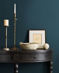 a wooden table with a bowl and two candles on it next to a framed photograph