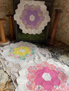 two quilts are sitting on the floor next to each other in front of a fireplace