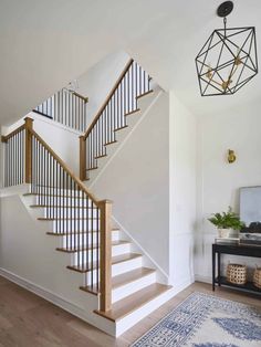 a white staircase with wooden handrails in a living room next to a black table