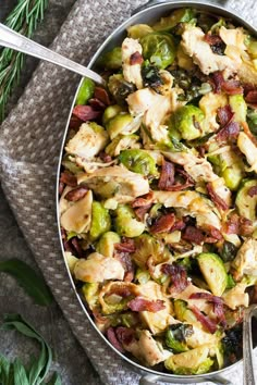 a pan filled with chicken and brussel sprouts on top of a table