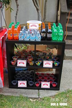 an outdoor party with plastic cups and soda bottles on display in front of the house