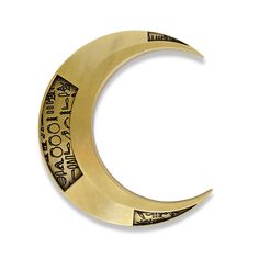 a gold crescent shaped brooch with writing on it