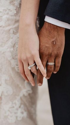 a close up of two people holding hands with rings on their fingers and wearing wedding bands