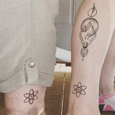 two people standing next to each other with matching tattoos on their legs, one has an atomic symbol and the other is a hot air balloon