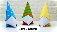 three origami paper gnomes on a white table with the words paper gnome above them