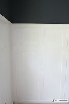 a white toilet sitting in a bathroom next to a wall with paneling on it