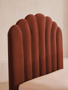 an upholstered headboard made out of red velvet with curved back rests on a white bed