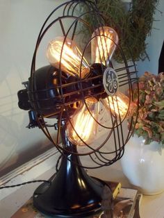 an old fashioned fan sitting on top of a table next to a potted plant