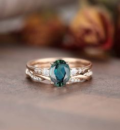 a ring with an oval green stone and two white diamonds on the side, sitting on a table