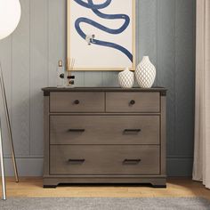 a dresser with two vases and a painting on the wall in a living room