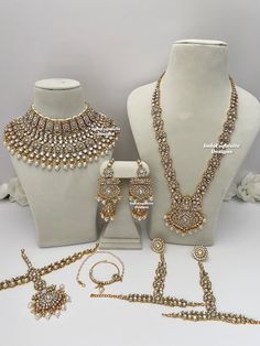 three pieces of jewelry sitting on display in front of white mannequins and flowers