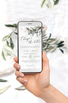 a woman holding up her phone with the wedding card displayed on it's screen