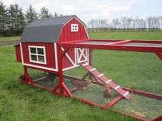 a red chicken coop in the middle of a grassy field