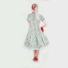 "This beautiful dress is summer-ready, made of unlined cotton piqué in white, with a blue, green, red, and yellow flower print. Blue piqué edges the neckline and sleeve cuffs. The dress has small blue-covered buttons all the way down the front. With a fitted bodice, the skirt is a full circle, flaring smoothly in back and with four front pleats. Short kimono sleeves; narrow matching belt. The label is from a shop, Bernard's Spokane. Please note: I show the dress with a crinoline beneath, to acce Multicolor Cotton Floral Dress With Short Sleeves, Cotton Full Skirt Summer Dress, Fitted Cotton Floral Sundress, Short Sleeve Cotton Floral Dress For Garden Party, Cotton Floral Dress Short Sleeve For Garden Party, Cotton Floral Dress With Short Sleeves For Garden Party, Fitted Multicolor Floral Cotton Dress, Fitted Multicolor Cotton Floral Dress, Green Cotton Floral Short Sleeve Dress