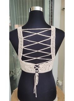 a mannequin wearing a white crochet top with ties on it's back