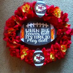 a football wreath with flowers around it that says when the leaves fall, it's time to play ball