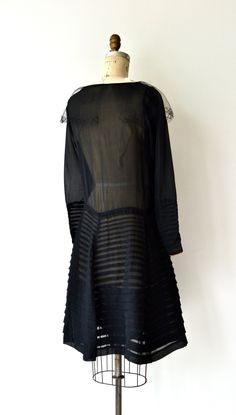 "Antique 1920s sheer black silk dress with scoop neckline, tulle trim, long sleeves with snap cuffs, enchanting crewelwork flowers on the bodice, classic drop waist and horizontal pleated skirt. This dress is in excellent condition, but as with all dresses of this era, should be worn with care as they are approaching 100 years old. [m e a s u r e m e n t s] Fits like: xs/small Bust: up to 34\" Waist: up to 33\" Hip: up to 42\" Length: 40\" Wrist circumference: 5 3/4\" [i n f o] Era: 1920s Brand/ Silk Dress With Sheer Sleeves For Daywear, Vintage Fitted Dress With Sheer Sleeves, Silk Long Sleeve Dress With Lace Trim, Black 1920s Style Dress For Vintage Events, 1920s Black Cocktail Dress, Silk Flapper Evening Dress, Black Art Deco Formal Dress, Sheer Silk Long Sleeve Dress, Black Long Sleeve Dresses For Vintage Events