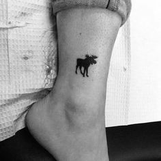 a black and white photo of a cow tattoo on the ankle, showing it's silhouette