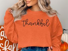 a woman with blonde hair wearing an orange sweatshirt that says,'thank you '