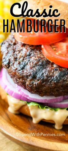 a close up of a hamburger on a plate with tomatoes and corn in the background