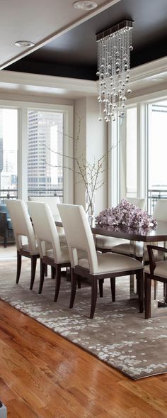 a dining room table with white chairs and a chandelier