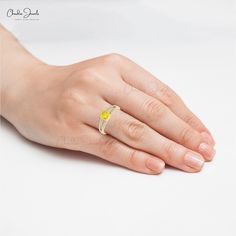 a woman's hand with a yellow diamond ring on her left hand and the other hand is holding it