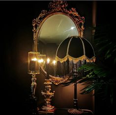 a table with a lamp and mirror on it in the dark room next to a potted plant