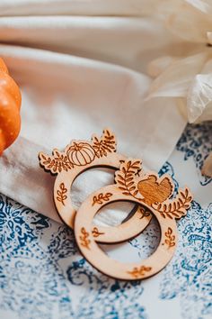 two wooden rings sitting on top of a blue and white cloth next to an orange pumpkin