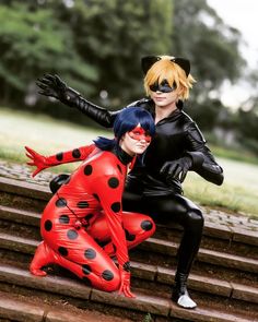 two people dressed as ladybug and catwoman pose for a photo on some steps