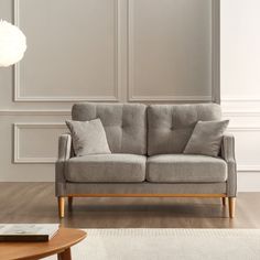 a gray couch sitting on top of a hard wood floor next to a wooden table