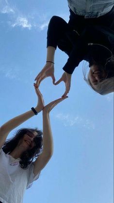 two women reaching up into the sky to reach something in the air with their hands