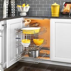 a kitchen with white cabinets and yellow dishes in the drawer rack on the left side