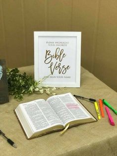 an open bible sitting on top of a table next to some markers and pencils