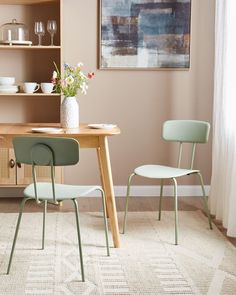 a dining room table with two chairs and a vase on top of it next to a shelf filled with dishes