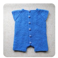 a blue knitted baby romper with buttons on the front and back, sitting on a white surface