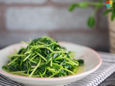 a white bowl filled with green vegetables on top of a table