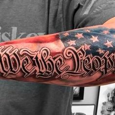 a man's arm with an american flag and we the people written on it