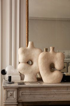 two large vases sitting on top of a table next to a lamp and mirror