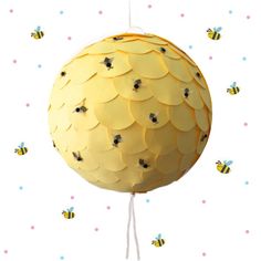 a paper ball with bees on it hanging from a string and surrounded by polka dots