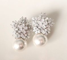 pair of earrings with white pearls and crystal stones on the end, against a plain background