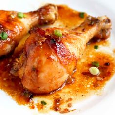 two chicken legs covered in sauce on a white plate