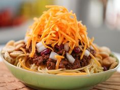 a green bowl filled with spaghetti and cheese