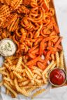 a box filled with pasta and sauce on top of a white table cloth next to some ketchup