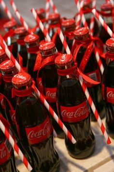 coca - cola bottles are lined up with red and white striped straws on them