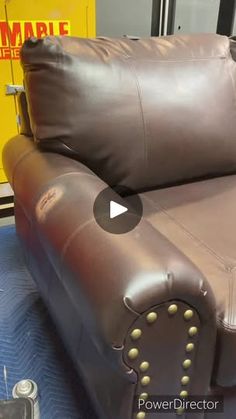 a brown leather recliner with studs on the arms and back is sitting in a showroom